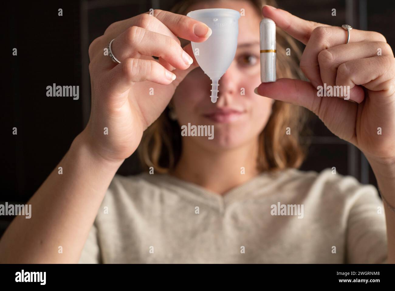 Donna che tiene i suoi prodotti mensili per la salute delle mestruazioni, tazza e tampone Foto Stock