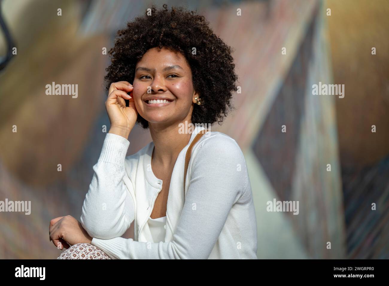 Giovane donna attraente seduta al sole e rilassante Foto Stock