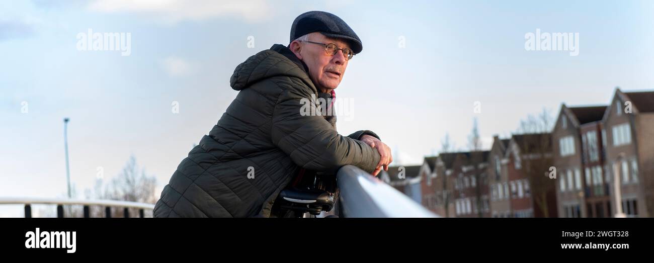Uomo anziano che va per una passeggiata sana e appoggiato su una ringhiera che guarda il paesaggio Foto Stock
