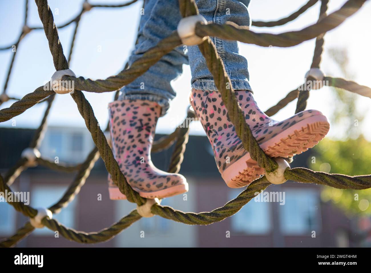La bambina è coraggiosa ad arrampicarsi in un parco avventura nel parco pubblico Foto Stock