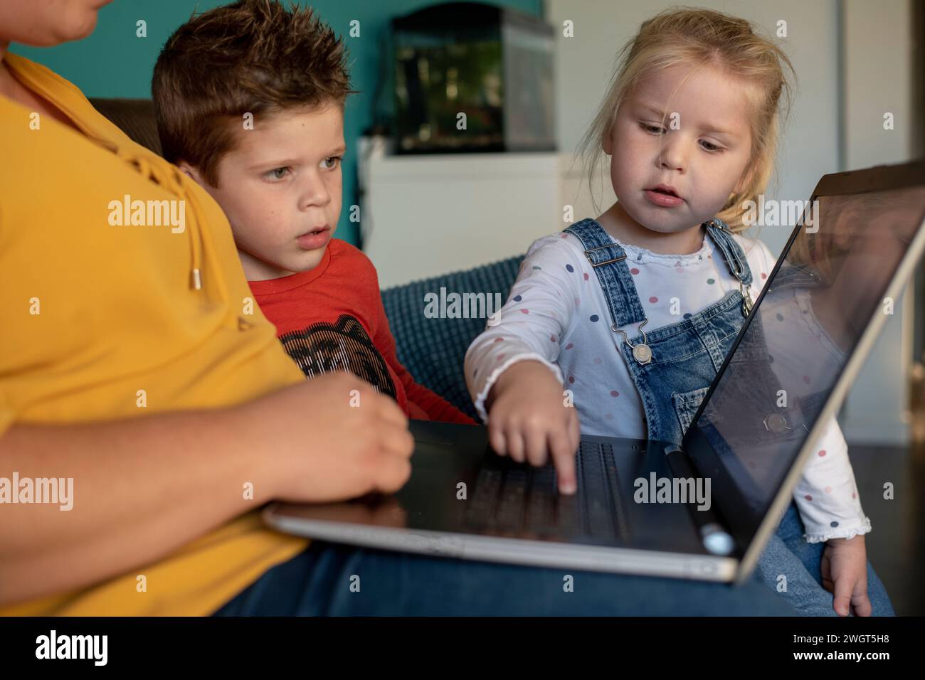 Madre seduta con suo figlio e sua figlia che lo educano e gli insegnano usando un portatile Foto Stock