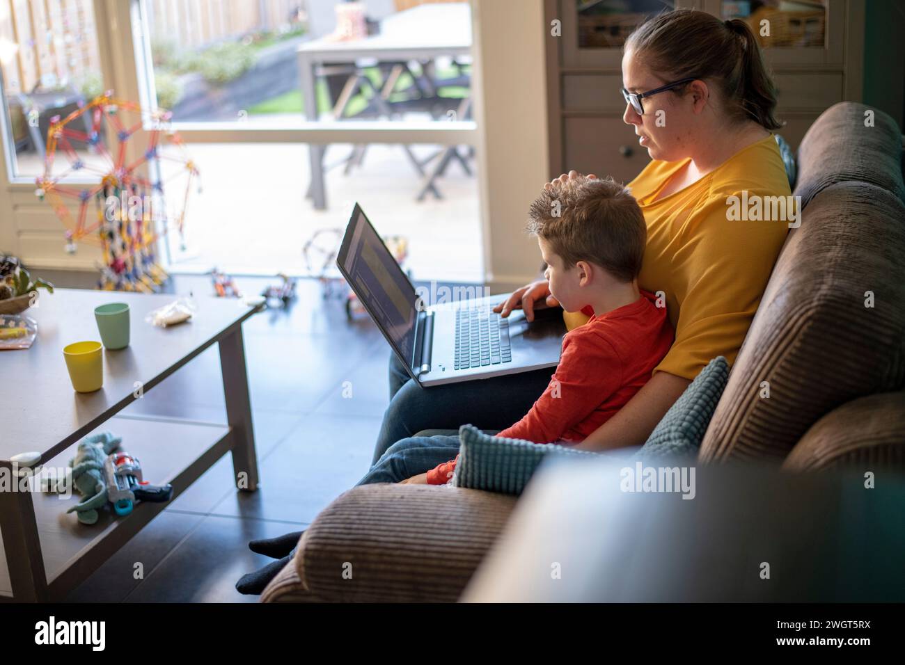 Madre seduta con suo figlio che lo educava e gli insegnava usando un portatile Foto Stock