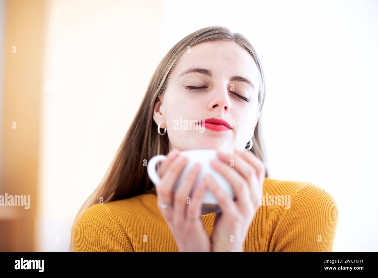 giovane donna con capelli biondi che si gode una bevanda calda Foto Stock