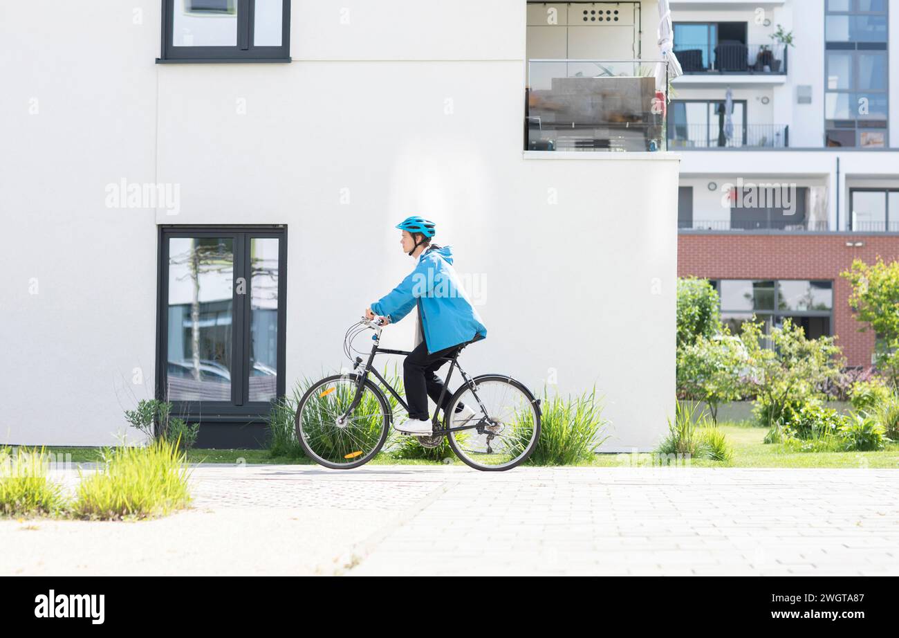Giovane in bicicletta in città con il casco Foto Stock