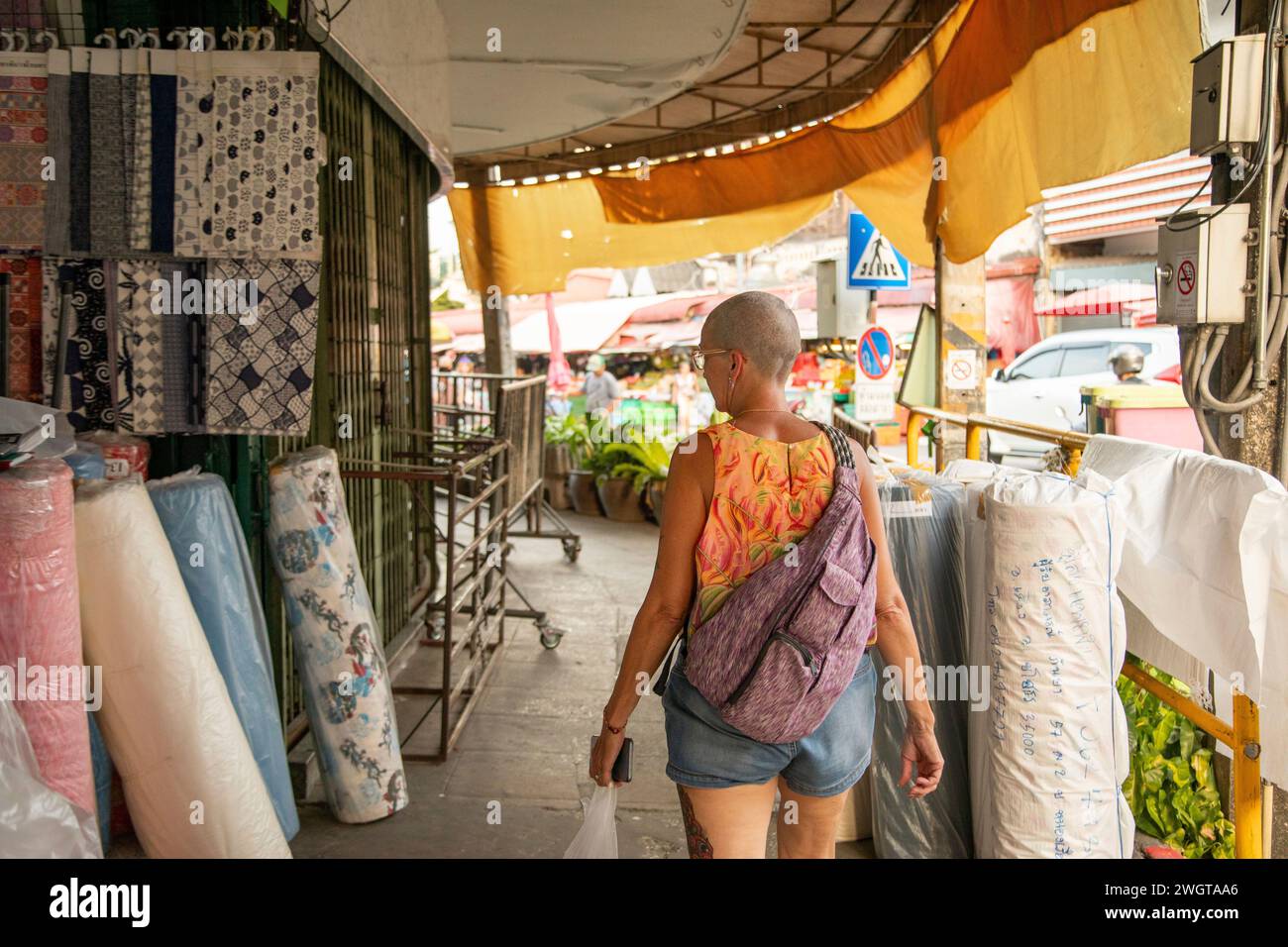 Una donna di mezza età, viaggiatrice solitaria, girovagerà per le strade locali, esplorando i negozi di materiali del nord della Thailandia Foto Stock