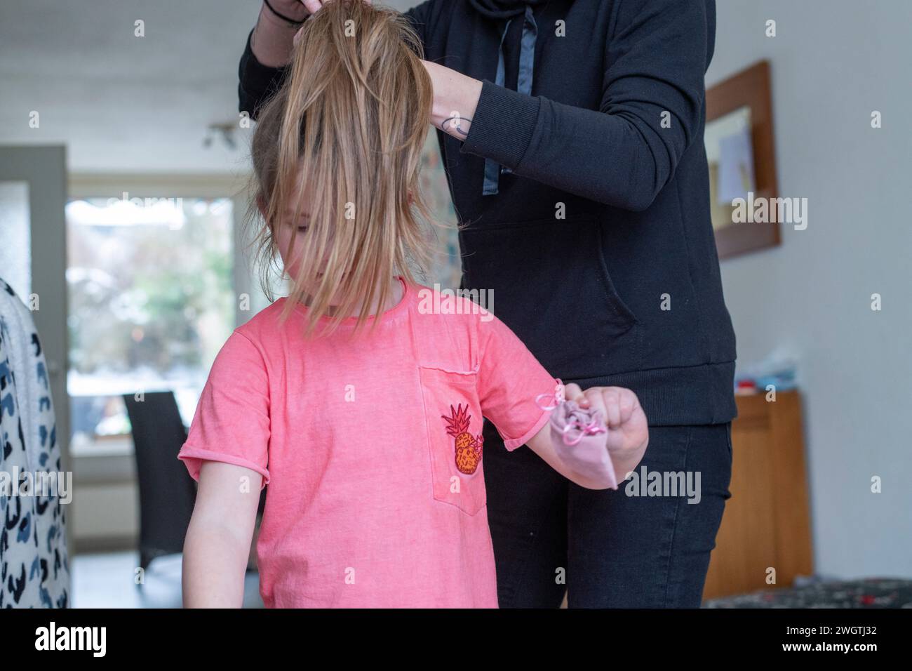 Mamma genitore che fa i capelli della sua giovane figlia in una coda di cavallo Foto Stock