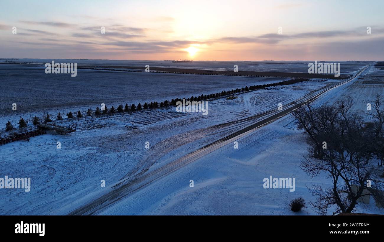 Un'autostrada panoramica coperta di neve si crogiola al caldo bagliore del sole. Foto Stock
