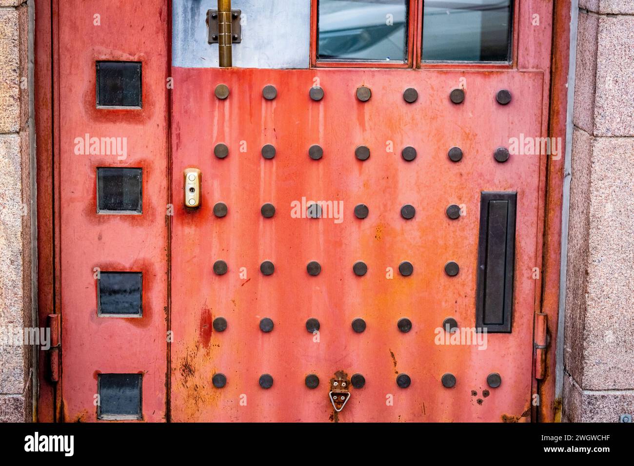 Un'insolita porta rossa di metallo punteggiata su un edificio di Helsinki, Finlandia Foto Stock