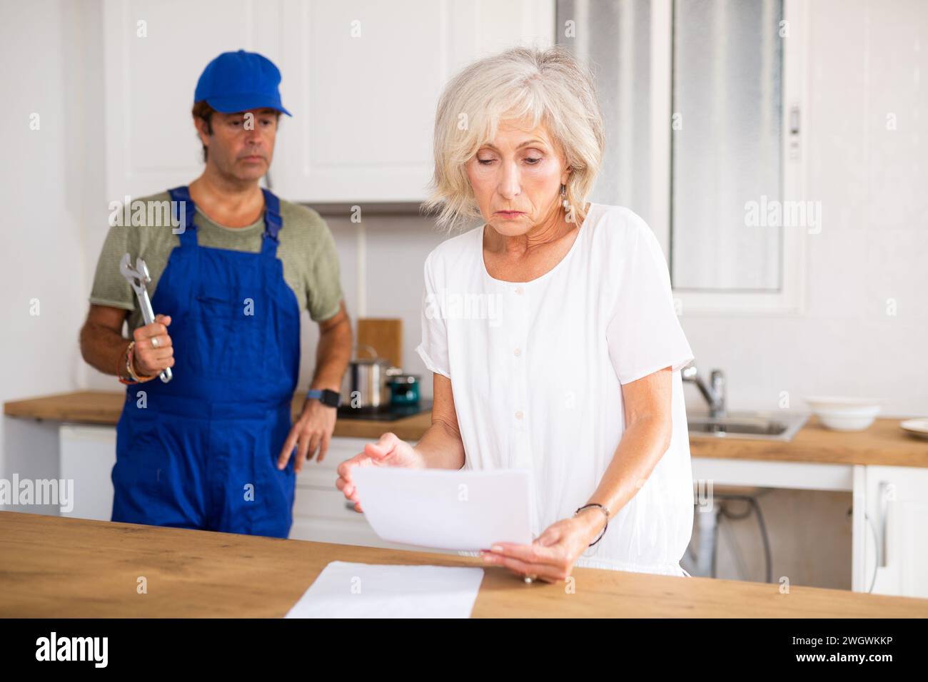 Ansiosa donna matura proprietaria di casa che legge i documenti contrattuali Foto Stock