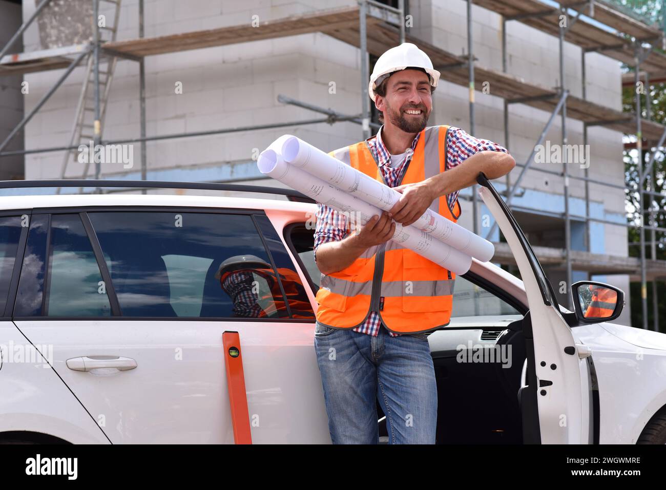 Ritratto sorridente construction manager / architetto sul sito durante la costruzione di una casa - la pianificazione e il controllo in loco Foto Stock