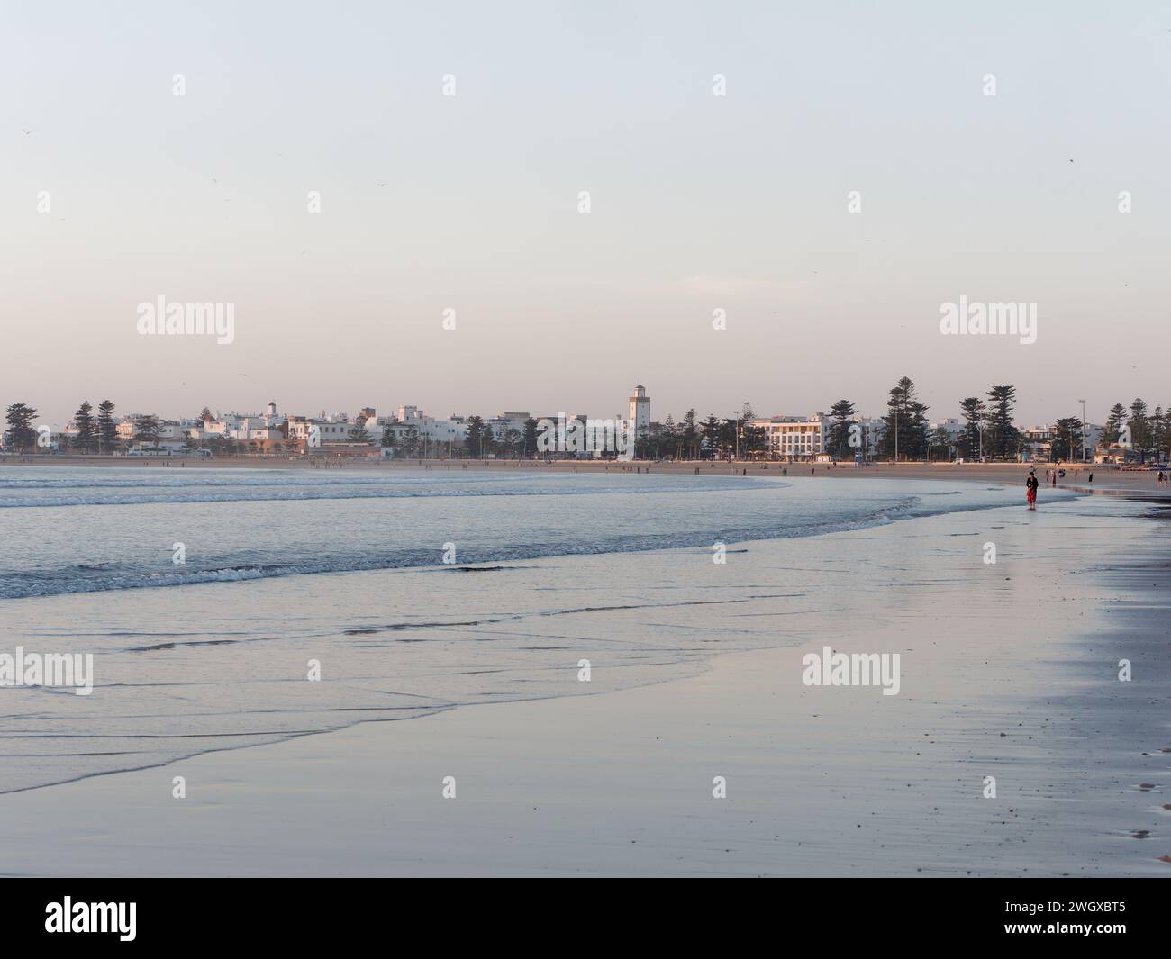 Persone su una spiaggia di sabbia una sera con la storica Medina alle spalle a Essaouira, Marocco, 6 febbraio 2024 Foto Stock