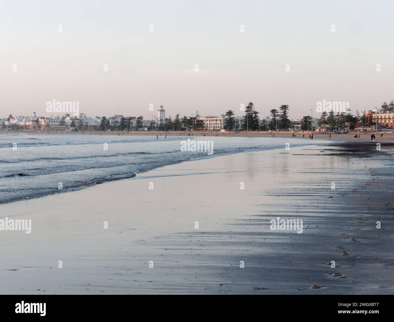 Persone su una spiaggia di sabbia una sera con la storica Medina alle spalle a Essaouira, Marocco, 6 febbraio 2024 Foto Stock