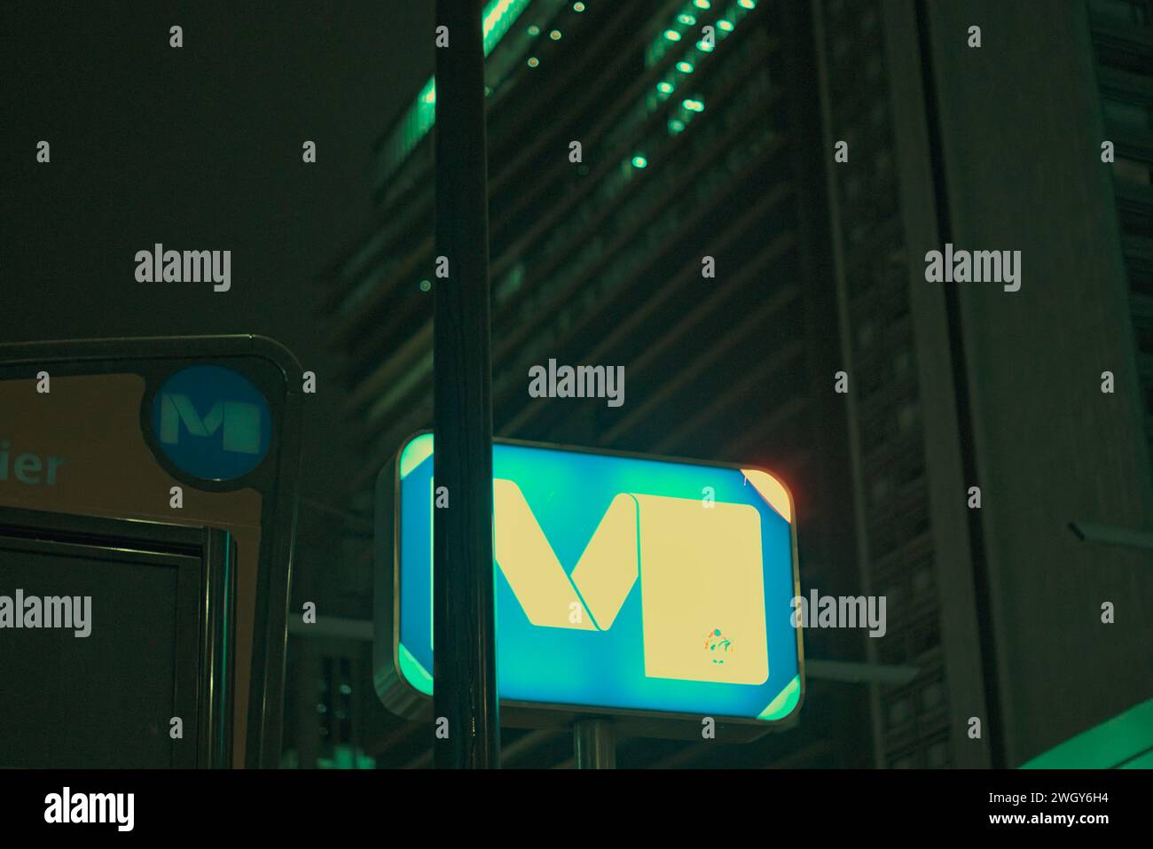 Bruxelles, Belgio. 5 febbraio 2024. Città notturna. Logo della metropolitana con la lettera M. la lettera brilla di notte. Stazione Roger. Facciata del grattacielo Foto Stock
