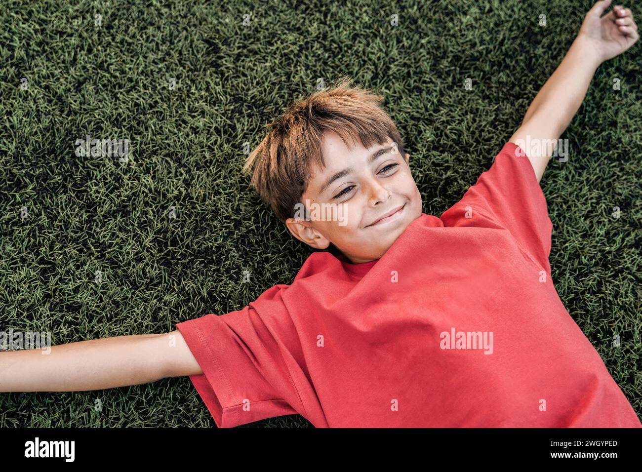 Bambino felice che giace su erba verde. Concetto di libertà, relax e felicità Foto Stock