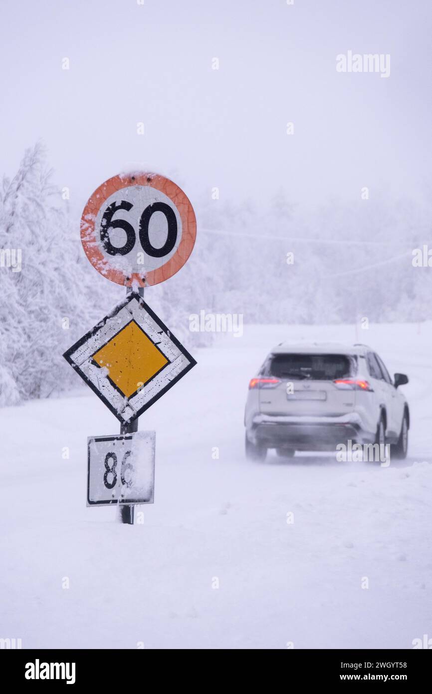 Auto che passa 60 km/h e segnali stradali prioritari in condizioni di guida gelide su un'autostrada a Senja, Norvegia, Scandinavia, Europa Foto Stock