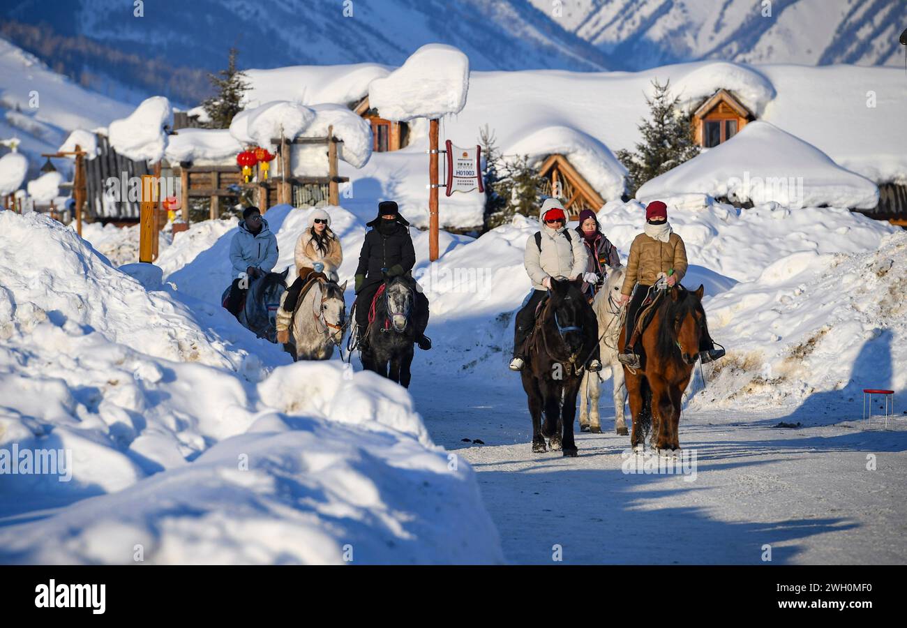 Pechino, la regione autonoma cinese dello Xinjiang Uygur. 5 febbraio 2024. I turisti cavalcano a cavallo nel villaggio di Hemu nella prefettura di Altay, nella regione autonoma di Xinjiang Uygur nella Cina nord-occidentale, 5 febbraio 2024. Nascosto all'interno della Prefettura di Altay, il villaggio di Hemu nello Xinjiang offre la perfetta fuga invernale. Con l'avvicinarsi del Festival di Primavera, il villaggio è diventato un punto di riferimento per i turisti. Credito: Ma Kai/Xinhua/Alamy Live News Foto Stock