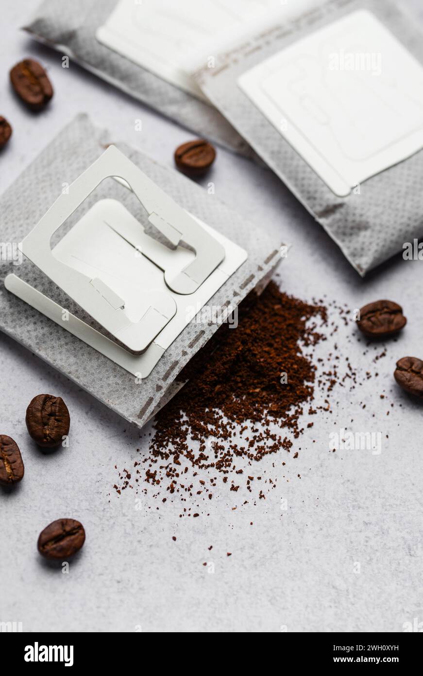 Versare i sacchetti di carta del caffè con i chicchi di caffè su uno sfondo grigio di cemento Foto Stock