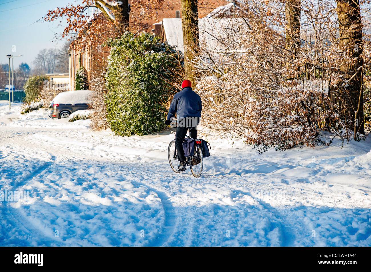 Beek, Limburgo meridionale, Paesi Bassi. 18 gennaio 2024. Vista posteriore di un uomo che va in bicicletta e guida su strada ricoperta da uno spesso strato di neve Foto Stock