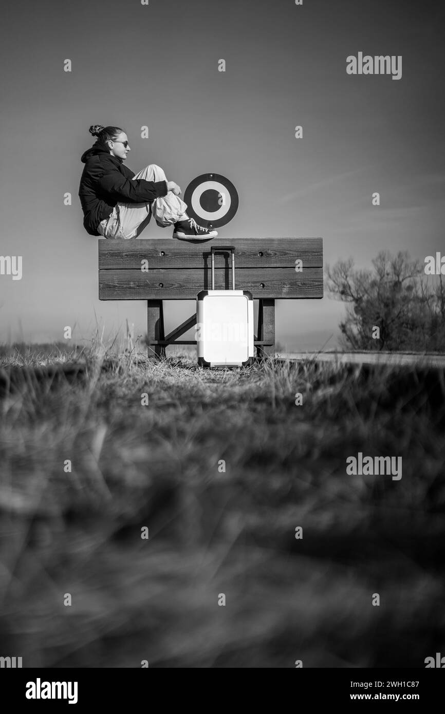 donna o ragazza con la valigia in attesa e seduta su un buffer sosta all'aperto in natura Foto Stock