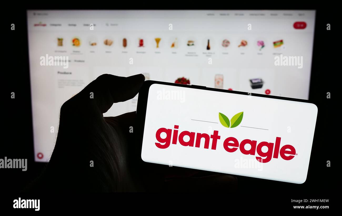 Persona che possiede un telefono cellulare con il logo della catena di supermercati americana Giant Eagle Inc. Di fronte alla pagina Web. Mettere a fuoco il display del telefono. Foto Stock