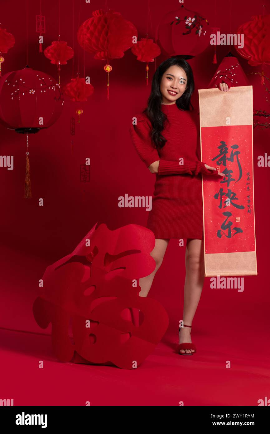 Atmosfera di Capodanno, una giovane donna asiatica che tiene un coupon per il Festival di Primavera su sfondo rosso Foto Stock