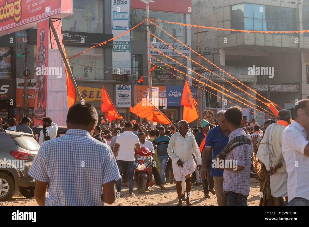 Hassan, Karnataka, India - 10 gennaio 2023: Le persone si riuniscono in una affollata strada indiana, adornata con bandiere arancioni, per celebrare il pro Shobha Yatra Foto Stock