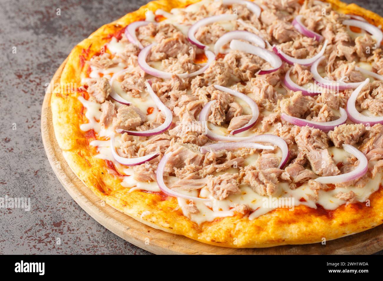 Pizza tonno e cipolla con tonno in scatola e cipolla rossa ravvicinata sul tavolo di legno. Orizzontale Foto Stock