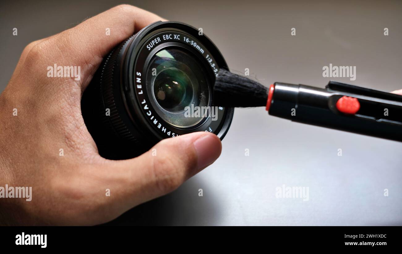 Pulizia di una lente mirrorless da 50 mm con un kit di utensili a spazzola. Foto Stock