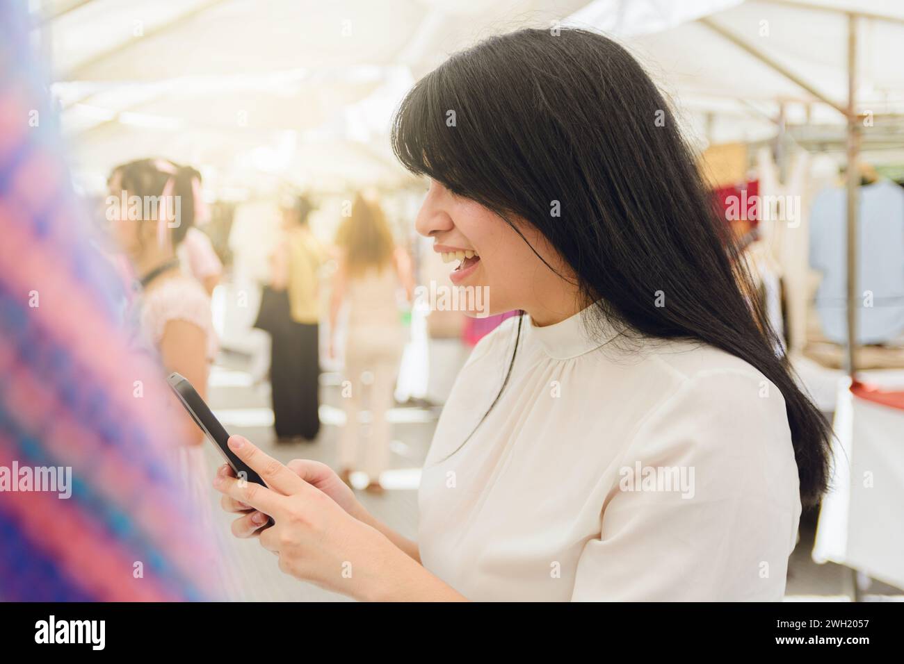 giovane donna ispanica latinoamericana felice che sta in piedi scrivendo messaggi sul suo telefono e controllando i social media mentre guarda l'abbigliamento giusto, il concetto tecnologico, le copie Foto Stock