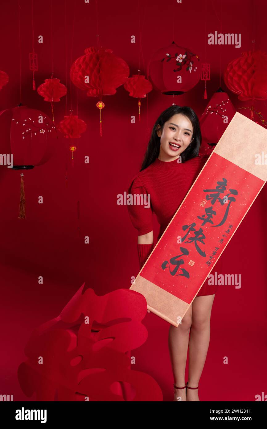 Atmosfera di Capodanno, una giovane donna asiatica che tiene un coupon per il Festival di Primavera su sfondo rosso Foto Stock