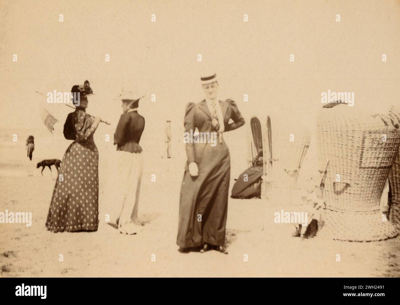Signore vestite e grandi sedie in vimini sulla spiaggia, Italia anni '1900 Foto Stock