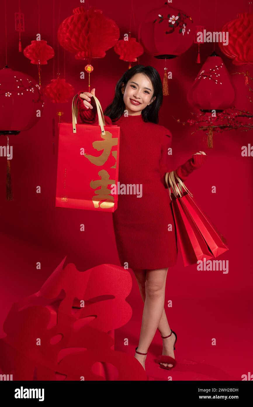 Shopping di Capodanno, una giovane donna asiatica che tiene in mano una borsa sullo sfondo rosso Foto Stock