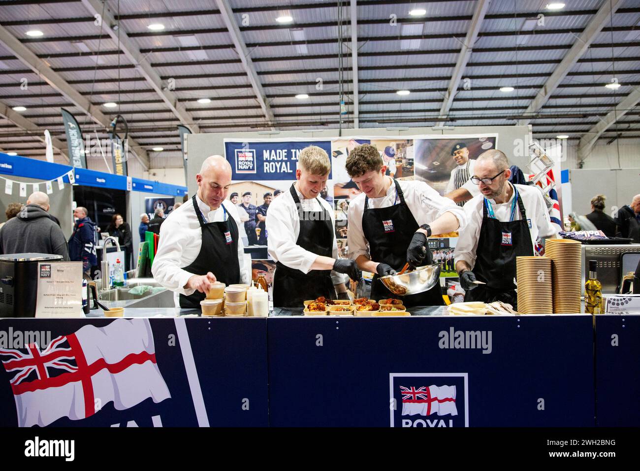 Gli chef della Royal Navy cucinano dal vivo alla fiera Source Food, drink, catering e ospitalità che si tiene a Westpoint Exeter Regno Unito, con espositori e marchi il 7 febbraio 2024 Foto Stock
