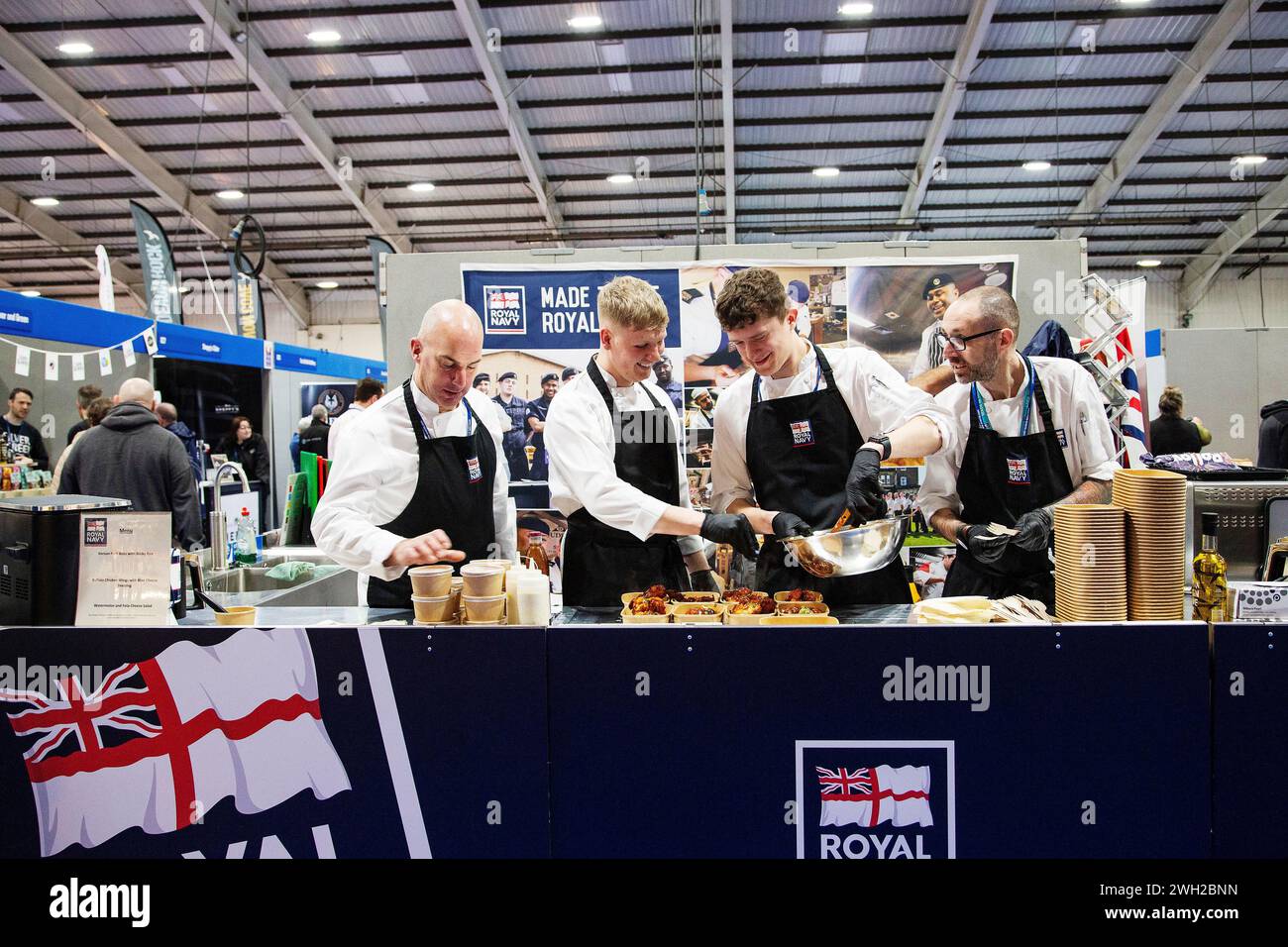 Gli chef della Royal Navy cucinano dal vivo alla fiera Source Food, drink, catering e ospitalità che si tiene a Westpoint Exeter Regno Unito, con espositori e marchi il 7 febbraio 2024 Foto Stock