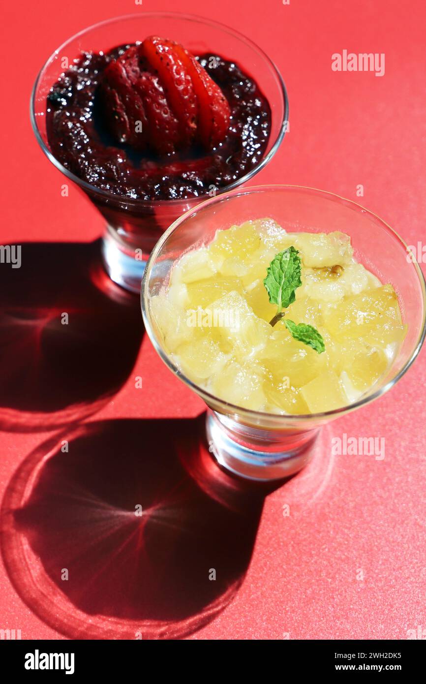 I due bicchieri di bevande ripiene di frutta su un tavolo, posizionati uno accanto all'altro. Foto Stock