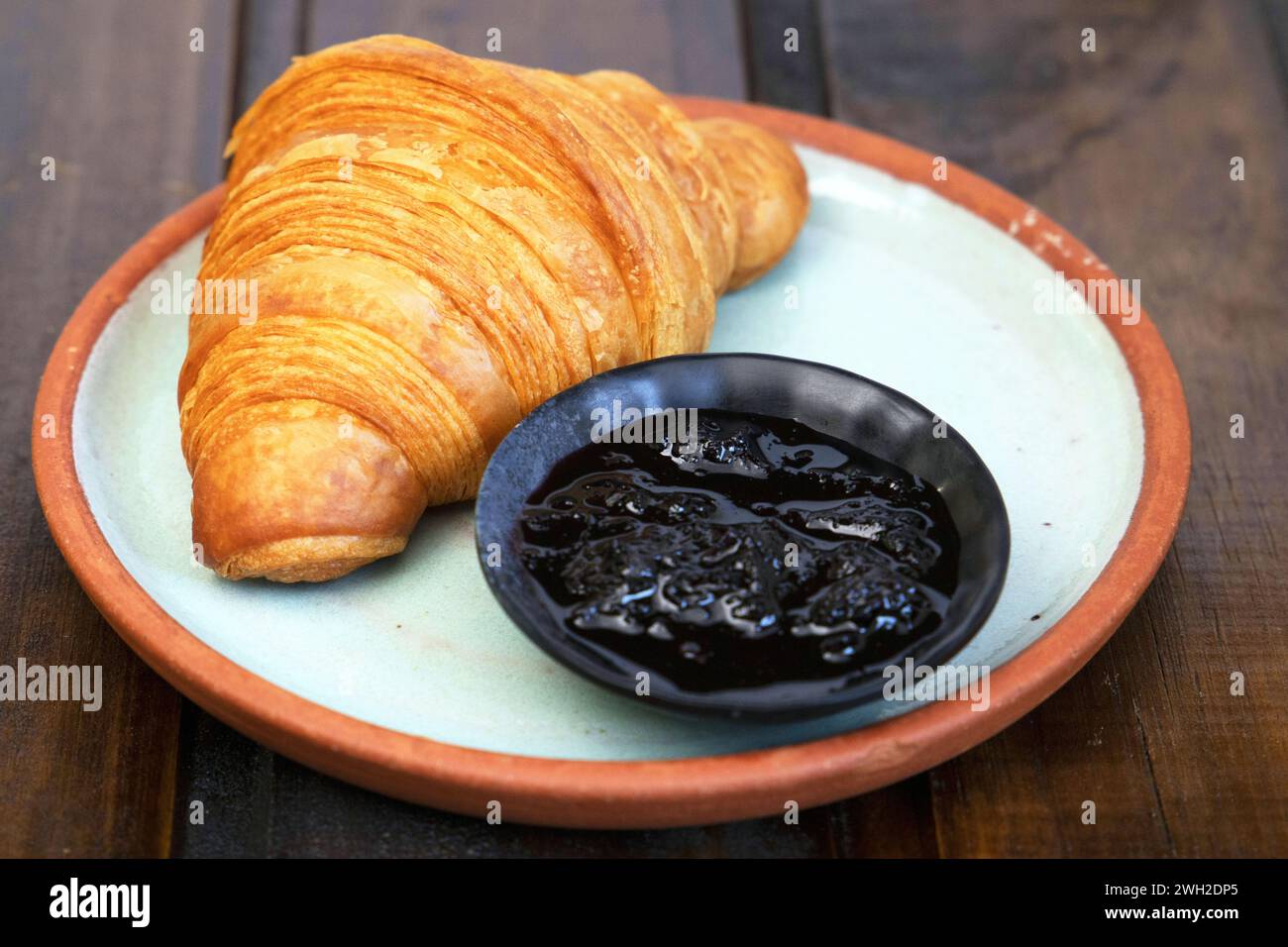 Un delizioso panino con croissant e un dolce preparato ad arte su un piatto. Foto Stock