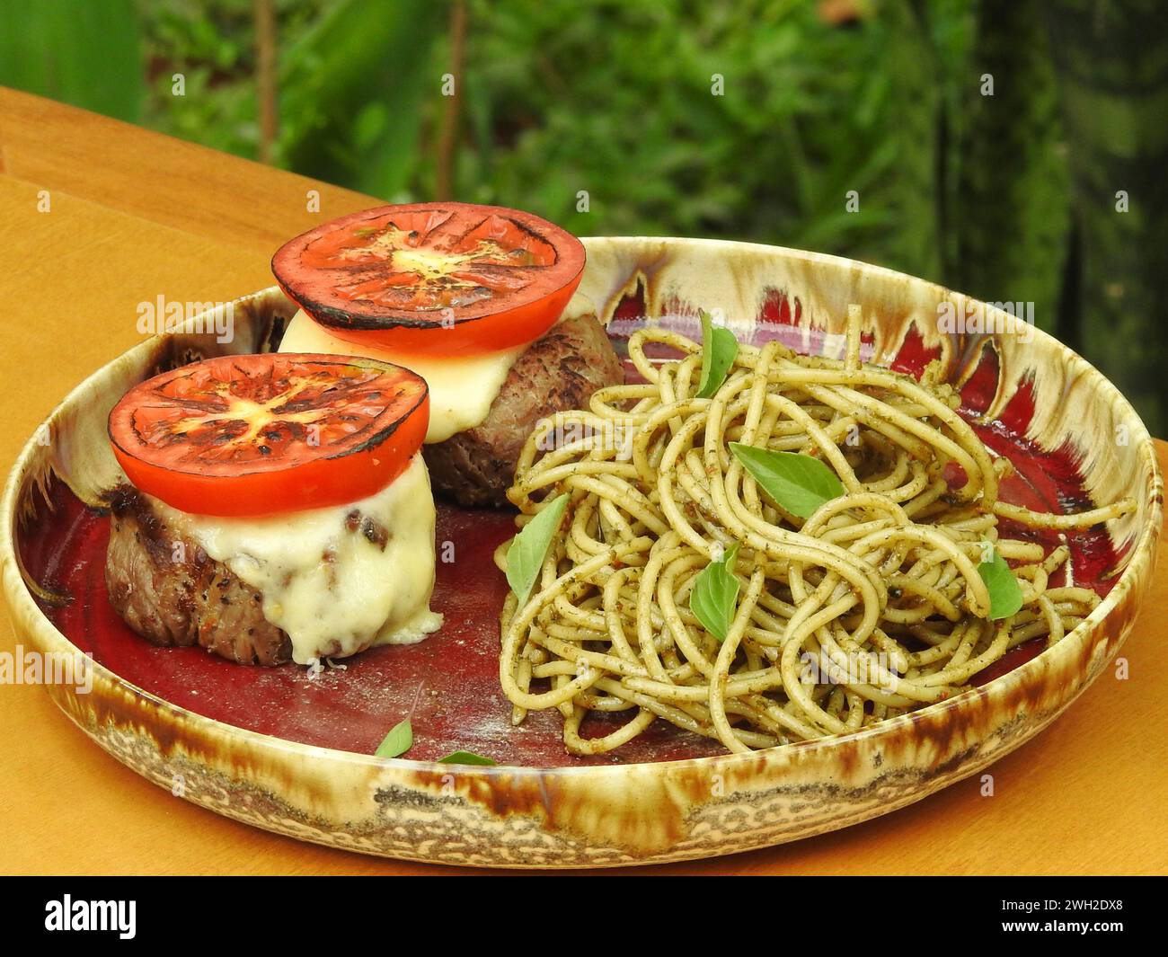 Delizioso filetto mignon abbinato all'insalata caprese e servito con spaghetti conditi con saporita salsa al pesto Foto Stock