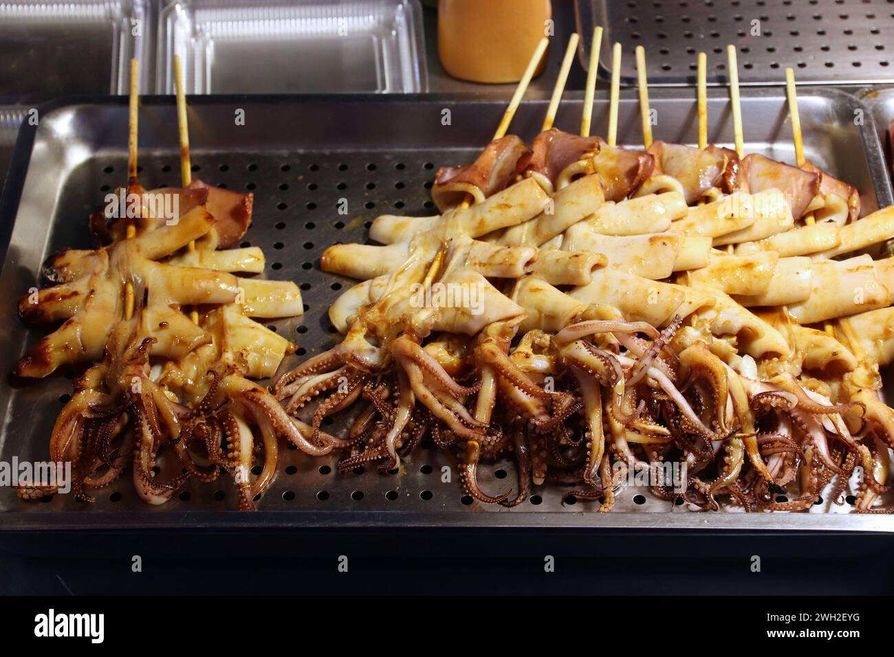 Mercato alimentare notturno di Taiwan - mercato notturno di Raohe a Taipei. Calamari e polpo al barbecue sul bastoncino. Foto Stock