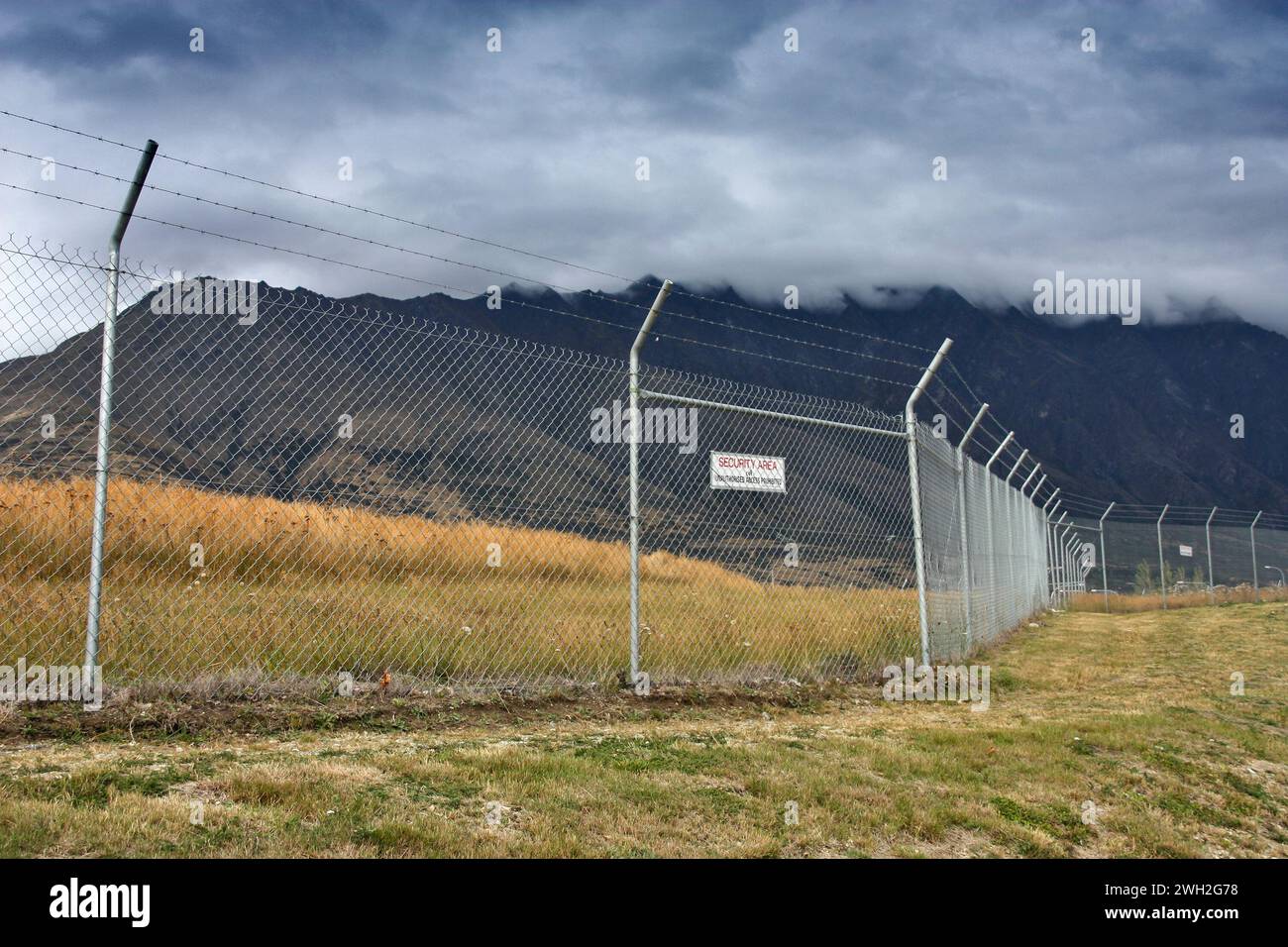 Alta recinzione con filo spinato che circonda il perimetro dell'aeroporto in nuova Zelanda. Foto Stock