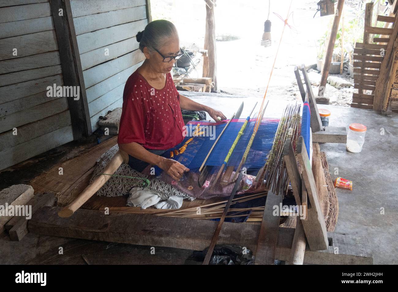 13.11.2023, Sukarara, Lombok, IDN - Frau bei der traditionellen Ikat-Weberei. 60-70 Jahre, Alltag, Arbeit, asiatisch, Asien, aussen, Aussenaufnahme, Frau, Gesellschaft, Handwerk, Handwerkskunst, Herbst, Herstellung, Ikat-Weberei, Indonesien, indonesisch, Jahreszeit, Kunsthandwerk, Land und Leute, Mensch, persona, QF, Querformat, Suedostasien, Sukarara, Textilien, traditionell, Tuchherstellung, Weben, Weberdorf, Weberei, Weberkunst, Wirtschaft 231113D624LOMBOK.JPG *** 13 11 2023, Sukarara, Lombok, IDN Woman at Traditional ikat Weaving 60 70 years, Daily Life, work, Asian, Asia, esterno, esterno Foto Stock