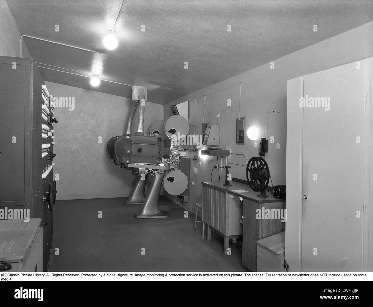 Dietro le quinte del cinema. Il cinema negli anni '1950 La sala proiettore di un cinema di Stoccolma. Vengono utilizzati due proiettori a pellicola. Dal momento che i film non si adattavano a un rotolo di pellicola, era importante che il macchinista fosse abile nel passare al proiettore successivo con il rotolo successivo al momento opportuno. L'operatore del cinema gestisce anche l'illuminazione nella sala cinematografica. Un pannello di controllo a sinistra controlla la luce nella sala cinematografica, le luci di scena, ecc. e anche la tenda. anni '1950 Foto Stock