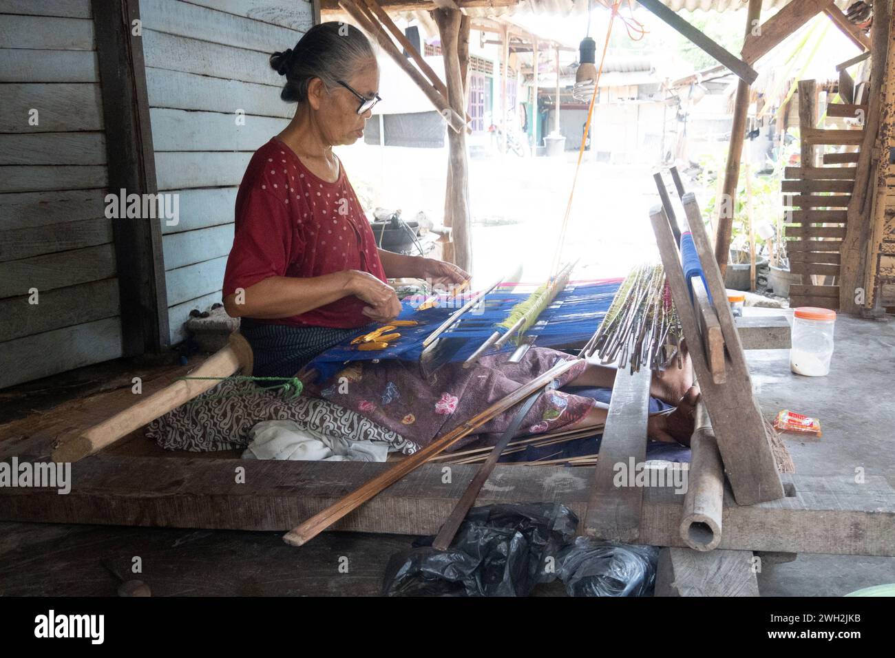 13.11.2023, Sukarara, Lombok, IDN - Frau bei der traditionellen Ikat-Weberei. 60-70 Jahre, Alltag, Arbeit, asiatisch, Asien, aussen, Aussenaufnahme, Frau, Gesellschaft, Handwerk, Handwerkskunst, Herbst, Herstellung, Ikat-Weberei, Indonesien, indonesisch, Jahreszeit, Kunsthandwerk, Land und Leute, Mensch, persona, QF, Querformat, Suedostasien, Sukarara, Textilien, traditionell, Tuchherstellung, Weben, Weberdorf, Weberei, Weberkunst, Wirtschaft 231113D625LOMBOK.JPG *** 13 11 2023, Sukarara, Lombok, IDN Woman at Traditional ikat Weaving 60 70 years, Daily Life, work, Asian, Asia, esterno, esterno Foto Stock