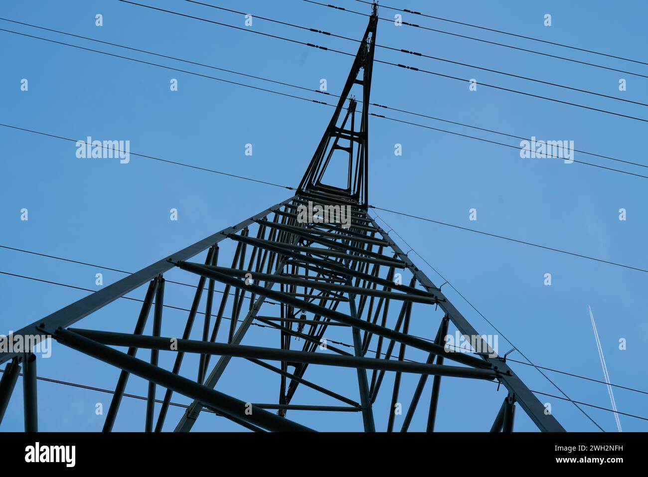 Struttura in acciaio del montante della linea elettrica con cablaggio ad alta tensione visto dal basso contro un cielo blu. Foto Stock