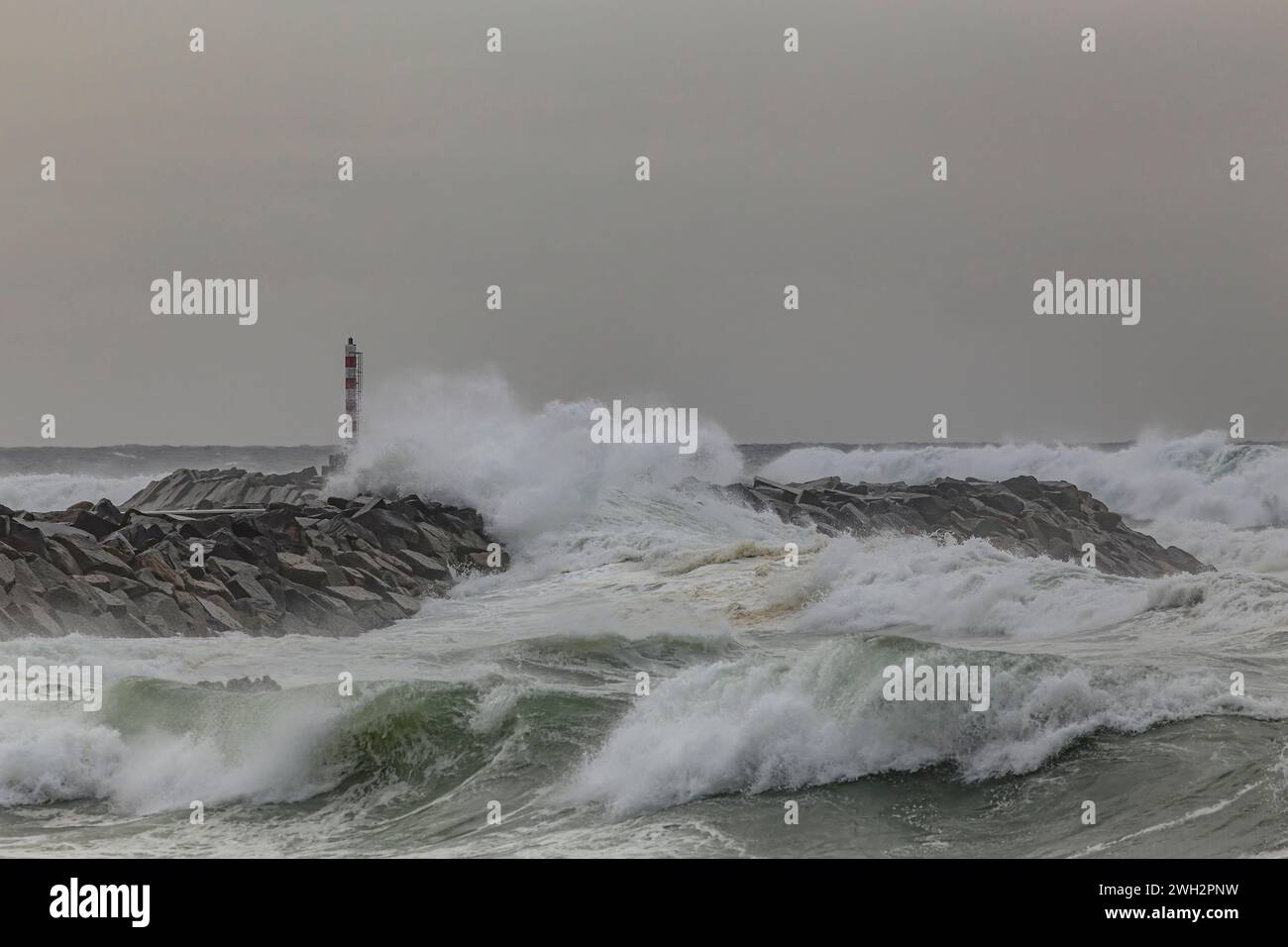 Breakwater e faro sotto tempesta dal piccolo porto di Angeiras, a nord del Portogallo. Foto Stock