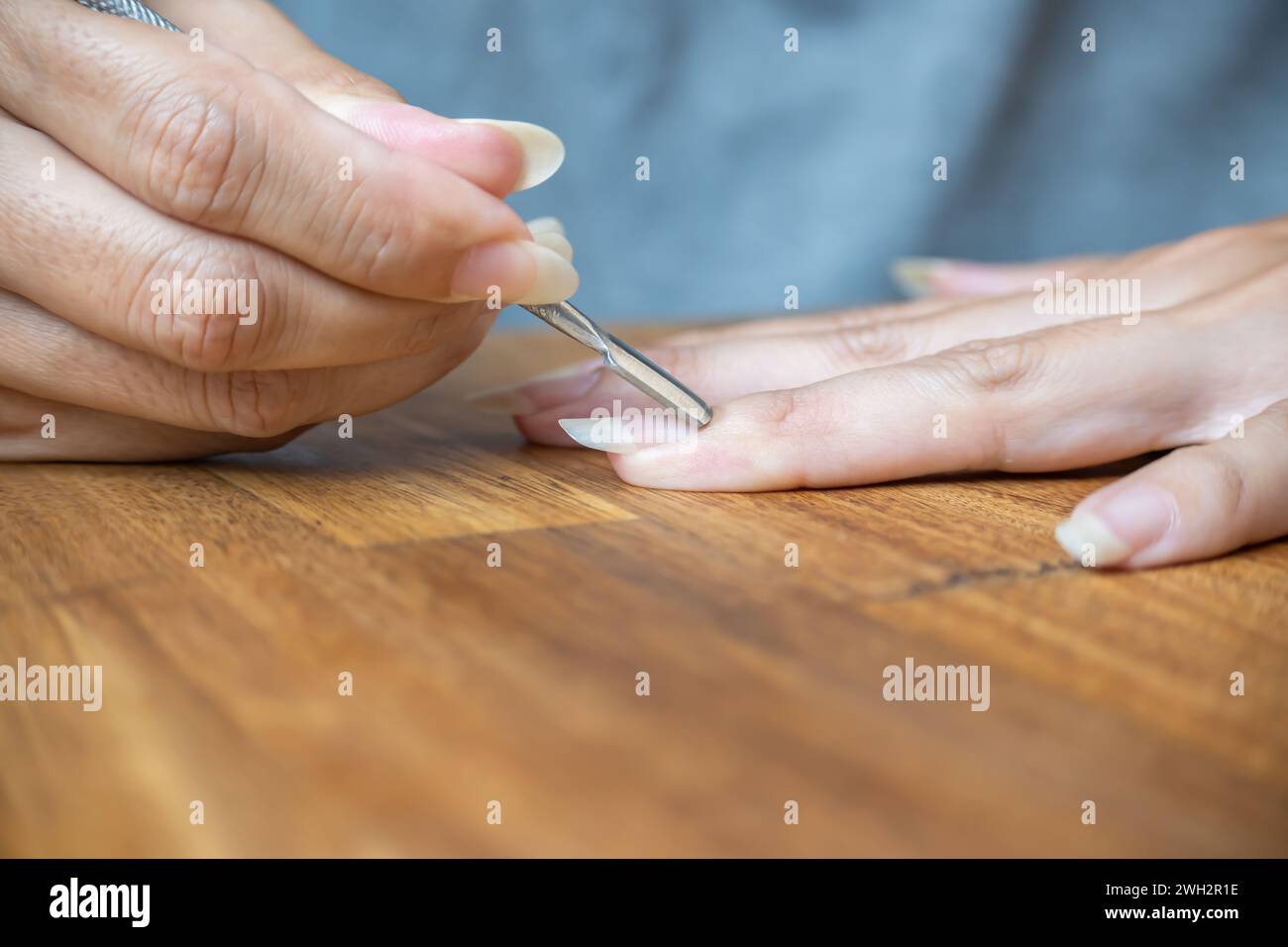 Le dita della donna utilizzano un pestello per cuticole a forma di pagaia. Foto Stock