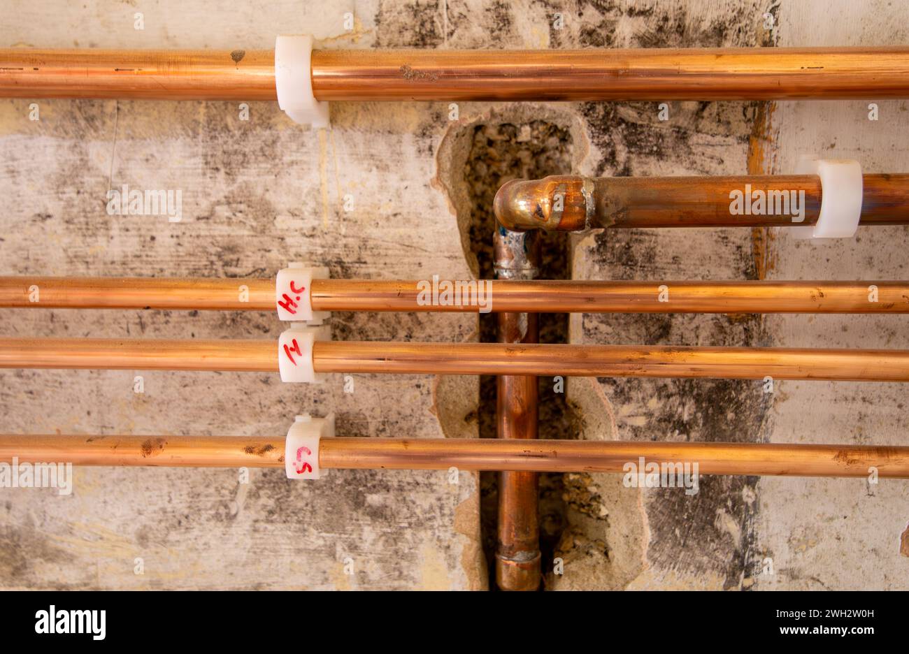Tubi per gas e acqua in rame lungo la parete con staffe di fissaggio in plastica nella ristrutturazione di case nel Regno Unito Foto Stock