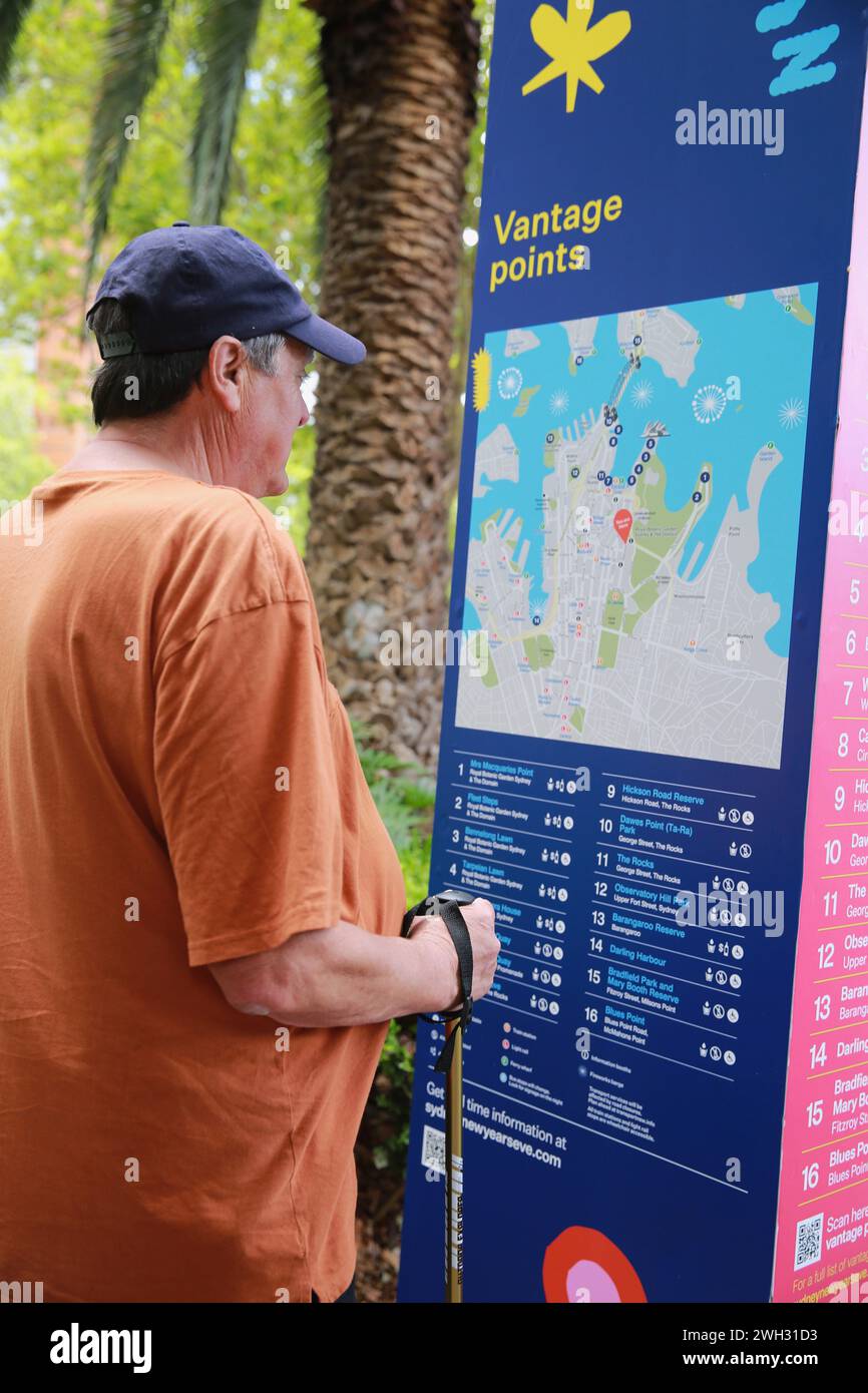 Un turista maschile che legge un cartello per i punti panoramici, Sydney Foto Stock