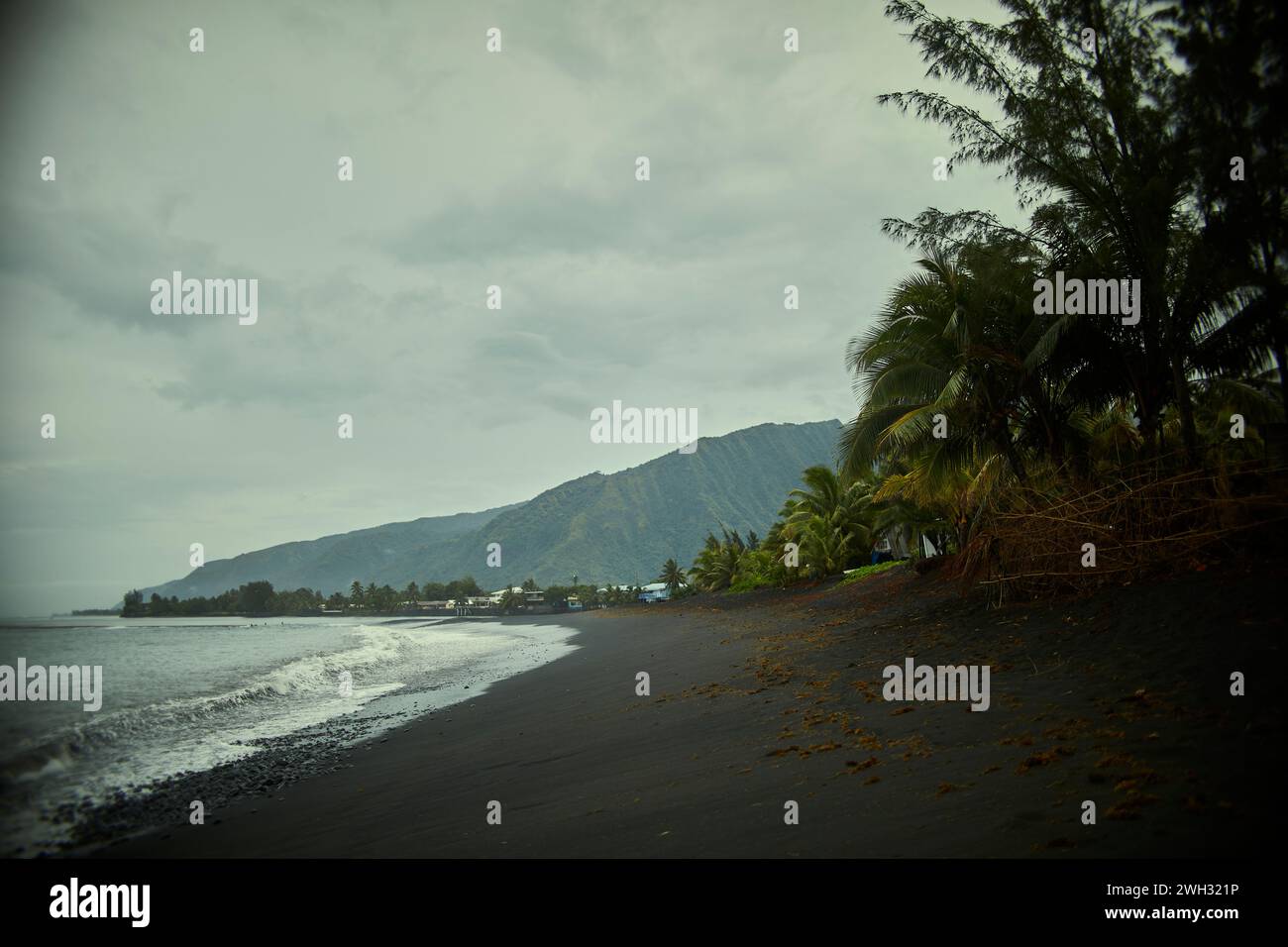 Spiaggia di sabbia nera su un'isola tropicale Foto Stock