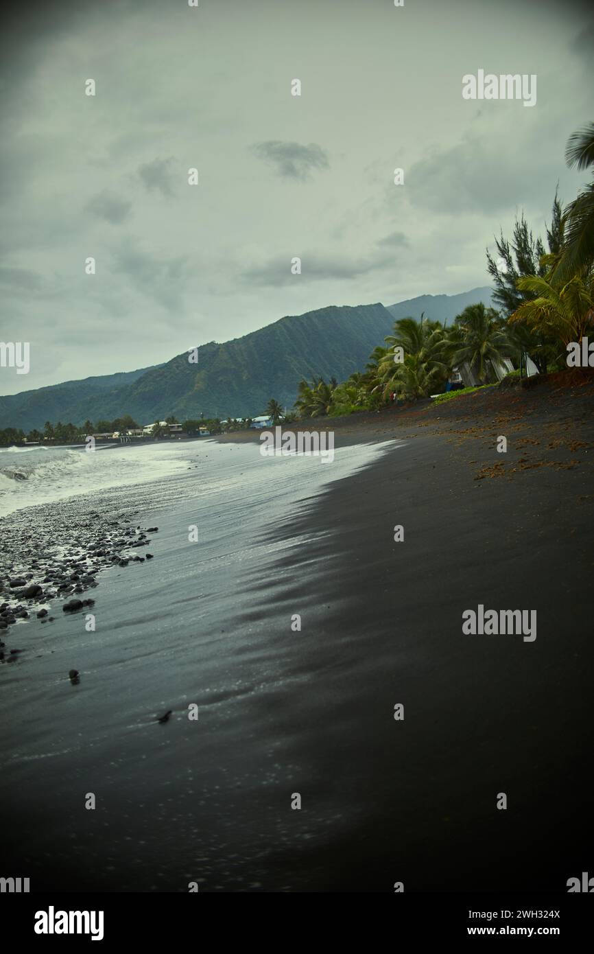 Spiaggia di sabbia nera su un'isola tropicale Foto Stock