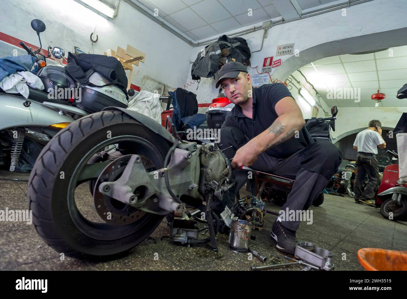 Mecanicien de moto, mobylette, vespa en pleine réparation dans son atelier meccanico al lavoro nella sua officina di riparazione Foto Stock